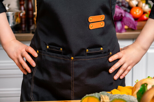 Woman chef in black apron in home kitchen with autumn harvest background. Professional kitchen apron mockup, culinary uniform, chef apparel, home cooking concept.