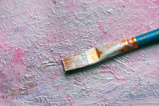 Pearlescent metallic acrylic paint mixed on a board with a used artist paint brush. Art and craft special effect paint supplies.