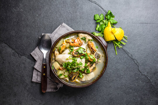 Seafood fish soup in clay bowls served with lemon and coriander. Top view, copy space