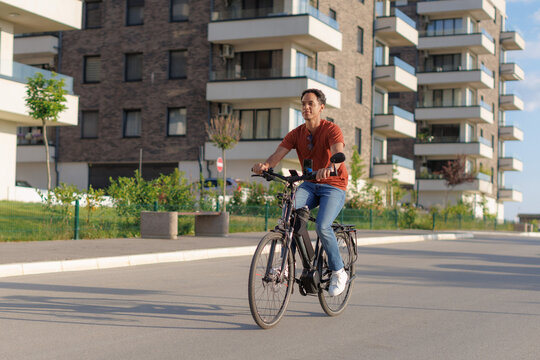 Man riding an e-bike on a sunny day near modern buildings in a city