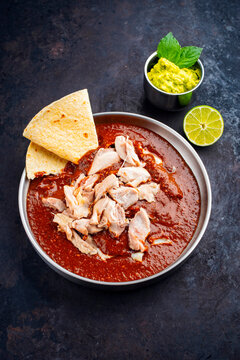 Traditional authentic artisan spicy chicken mole poblano served as close-up in a design bowl with avocado guacamole and fresh tortilla