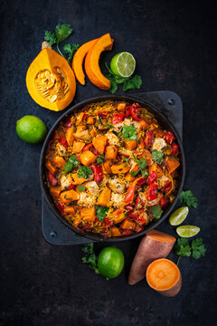Slow cooked casserole dish  healthy yummy spicy Italian one-pan role stew vegetable pumpkin, sweet potato, chicken and rice served as top view in a design casserole