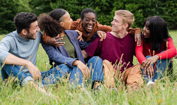 Group of Diverse Friends Embracing and Laughing in Grass Field
