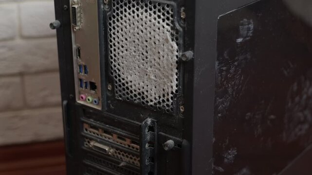 Dusty computer case cooling fan overheating. Extremely dirty and dusty black desktop computer case requiring cleaning of the cooling system fan, indicating potential overheating issues