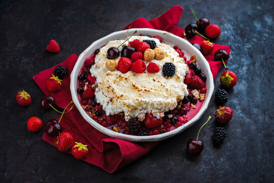 Oven baked meringue ricotta souffle with mixed fresh berries and amarettinis served as dessert on a design plate