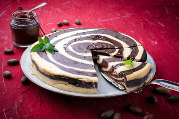 Fototapeta premium Artisan homemade baked zebra black-white cheesecake pie with dark chocolate served as close-up on a design plate