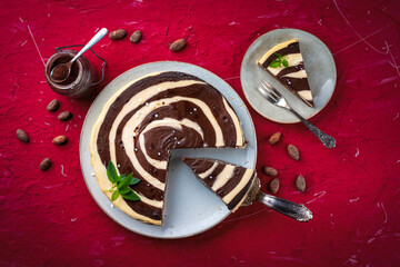 Obraz premium Artisan homemade baked zebra black-white cheesecake pie with dark chocolate served as top view on a design plate