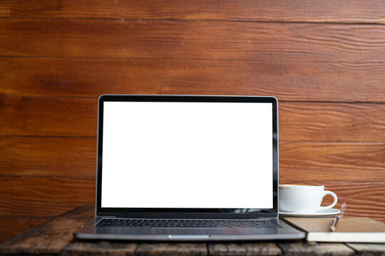 Mockup of laptop computer with empty screen with coffee cup and smartphone on table of tree branch shadow the cafe coffee shop background,White screen