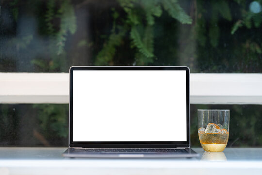 Mockup of laptop computer with empty screen with coffee isolate on wooden office desk in coffee shop like the background ,White screen