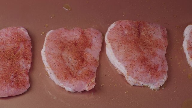 Seasoned pork chops cooking on a flat top griddle