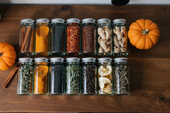 arrangement of spice jars and pumpkins on wooden table evokes autumn and culinary creativity