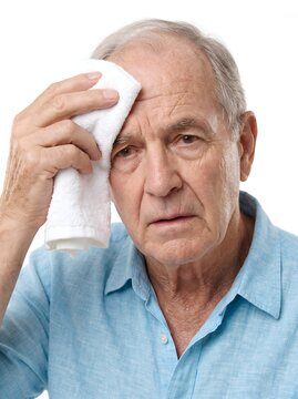 Sweating senior man wiping forehead with towel, elderly male suffering from fever or heatstroke, sick pensioner with flu symptoms on white background