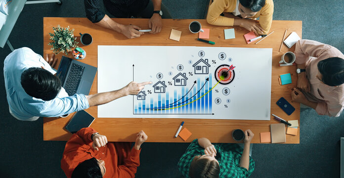 Business team analyzing real estate market trends with graphs and figures, discussing financial projections in modern office environment. Bitwise.