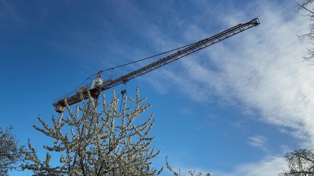 Construction crane jib rotating against blue sky
