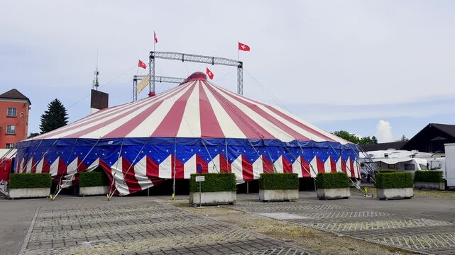 Wide View of a Traveling Circus Setup with Big Top Tent, Transport Trailer and Rigging Mast, Mobile Show Arriving in a Small European Town on a Sunny Day, No People