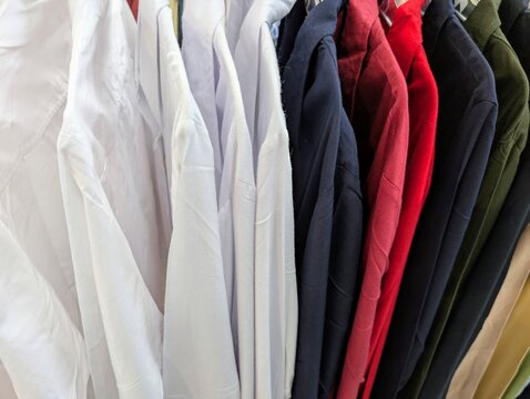 Various colorful shirts and jackets hanging neatly on a rack in a clothing store