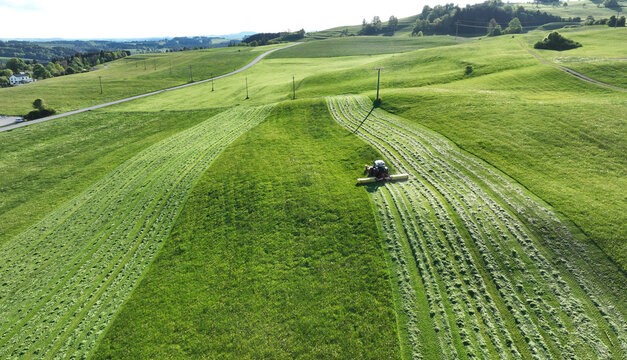 Drohnenaufnahme von einem Traktor der im Sommer ein Feld m&auml;ht