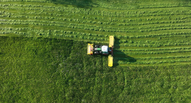 Drohnenaufnahme von einem Traktor der im Sommer ein Feld m&auml;ht