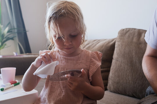  Funny cute child looking focused and independent while blowing dry her bedhead hair at home.