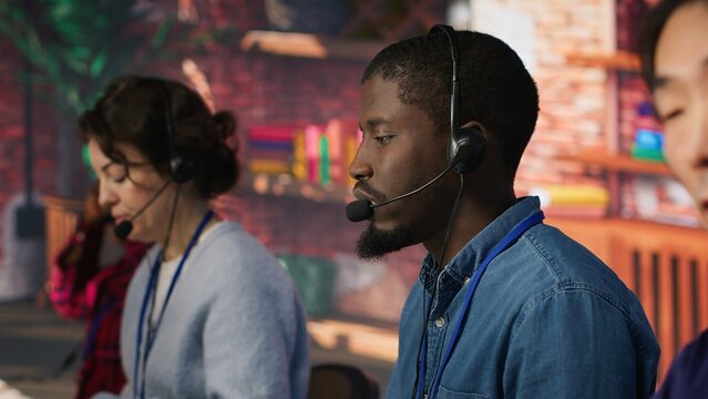 Multiethnic call center agents help clients reset passwords and restore account access while working together in a diverse customer service office.