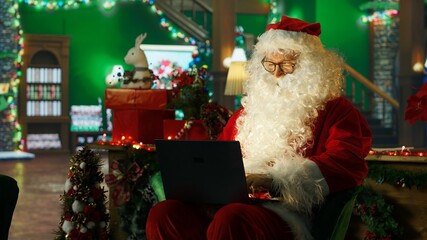 Fototapeta premium Smiling Santa Claus posts online to spread positivity and holiday joy while helping children feel a sense of wonder during Christmas.