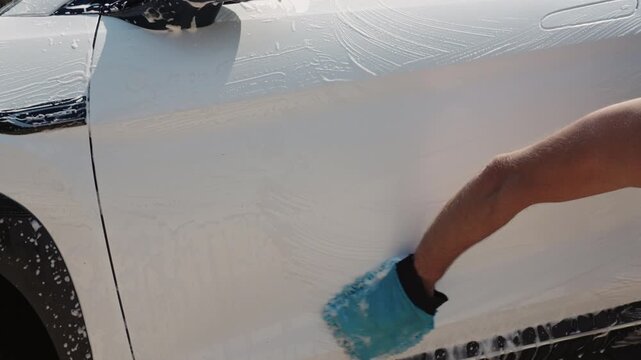 Car wash. Car in washing process. Carwash station. Washing car in workshop. Professional work. Car washer doing manual foam washing in auto detailing service