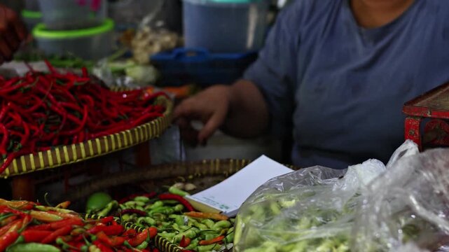 Close up of a cash transaction at a traditional wet market, hand paying with Indonesian Rupiah banknotes for fresh shallots and vegetables