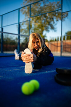 Woman athlete stretching on blue padel court
