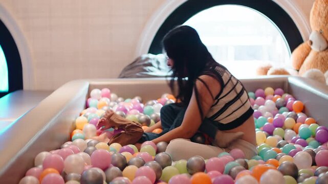 Mother and son having fun together in a colorful indoor ball pit