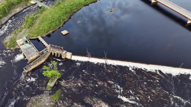 Aerial View of Howland, Maine River Dam Spillway and Flowing Water Over Weir With Nearby Green Banks