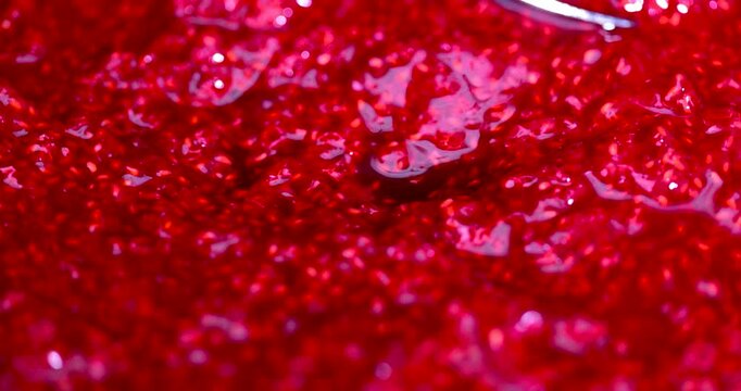 Red grated raspberries in the process of filling with white sugar, grains of crystalline sugar fall on the moist surface of the mashed raspberries