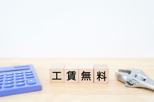 工賃無料。電卓と工具のブロック文字。ビジネスイメージ。コピースペースあり
