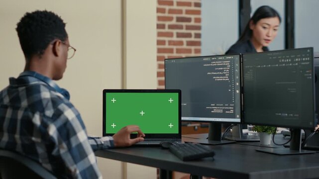 Database designer works at a desk with chroma key screen replacement, combining algorithm development, software testing and mockup presentation