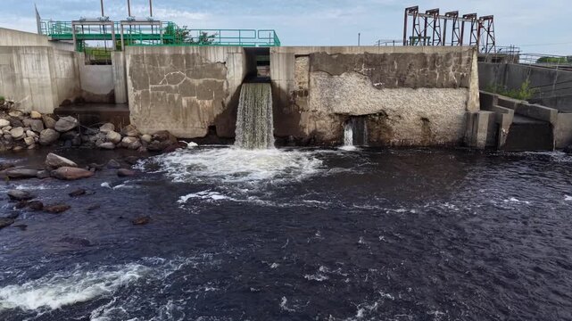 Howland, Maine Dam Spillway With Industrial Outflow Pouring Water Into Dark River Below