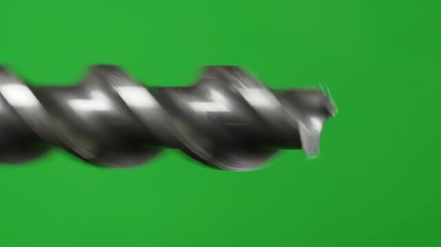 Close up of a metallic wood drill bit spinning rapidly against a bright green screen background for easy compositing and motion graphics