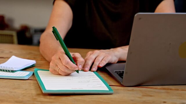 Person writing notes and drawing diagram at desk