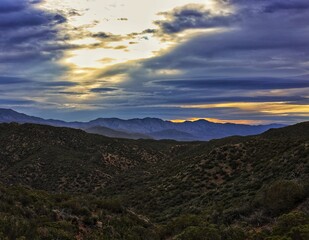 Obraz premium Golden Sunbeams Piercing Dramatic Clouds Over Desert Ridge