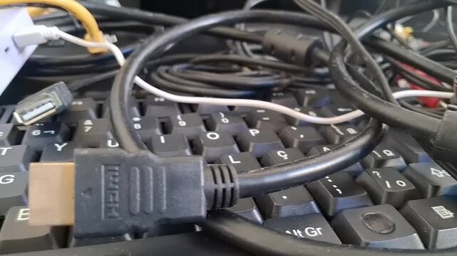 Tangled computer cables on a keyboard. Messy electronic wires and hardware equipment.