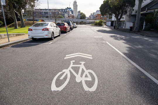 Bicycle stencil lane marking or&nbsp;a white painted bike symbol with directional chevron markings stamped on an asphalt road surface in North Melbourne, Australia, near some modern residential buildings
