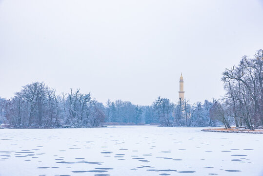 Winter view of the UNESCO Lednice Minaret tower beyond the frozen lake covered with snow in Czechia.