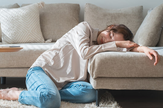 A woman dozing off on a sofa in the sunlight.