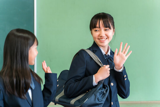 Smiling middle school and high school girls greeting friends in a school classroom as they go to school.