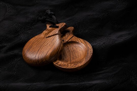 Traditional flamenco castanets resting on dark textured fabric.
