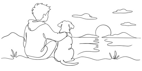 Boy and dog sitting on beach watching beautiful sunset over the ocean