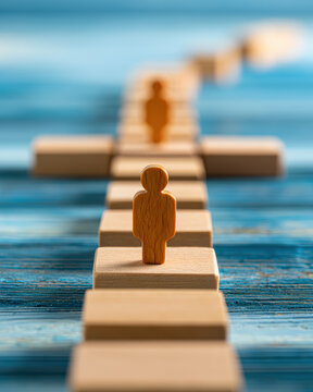 Wooden human figures stand on a boardwalk path with stairs, symbolizing progress, leadership, and journey against a blurred blue background.