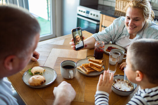 Family video calling grandparent during breakfast at home