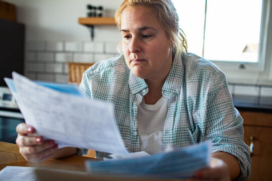 Concerned woman reviewing household bills at kitchen table