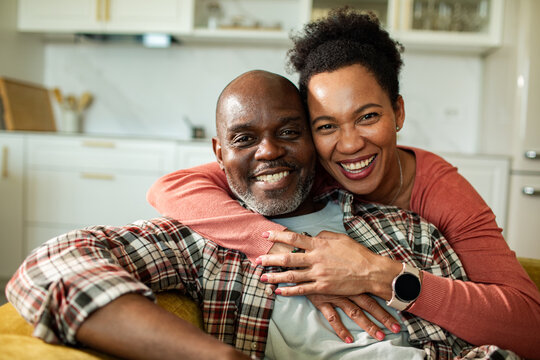 Smiling middle-aged couple embracing on couch at home