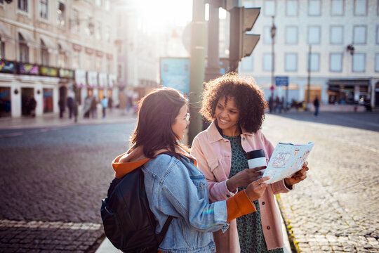 Two friends checking a map in sunny city square