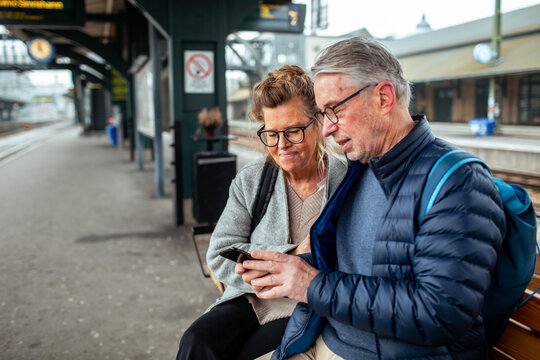 Senior couple using smartphone at railway platform